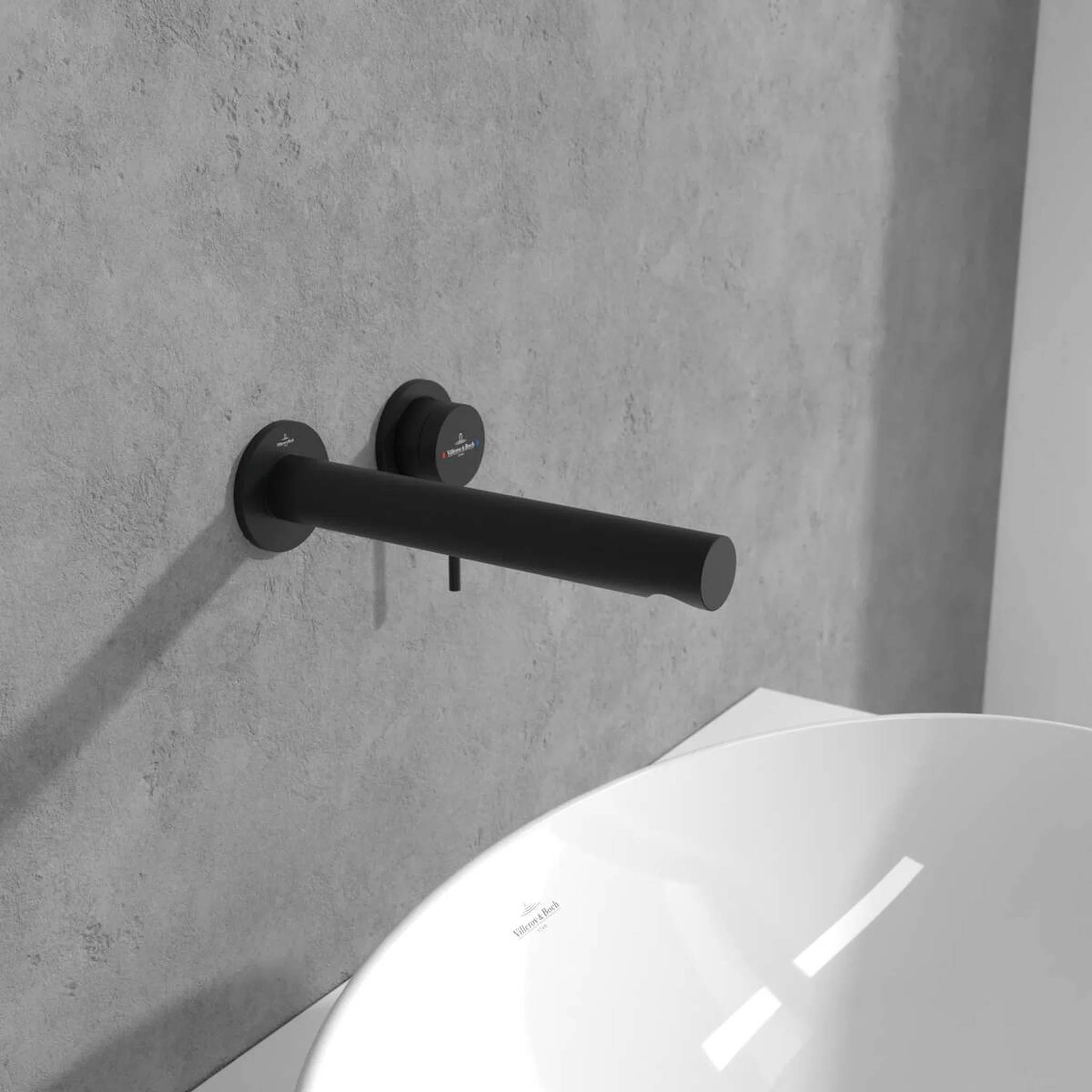 Schwarzer, an der Wand montierter Wasserhahn über einem weißen Waschbecken an einer grau strukturierten Wand im modernen Badezimmer.