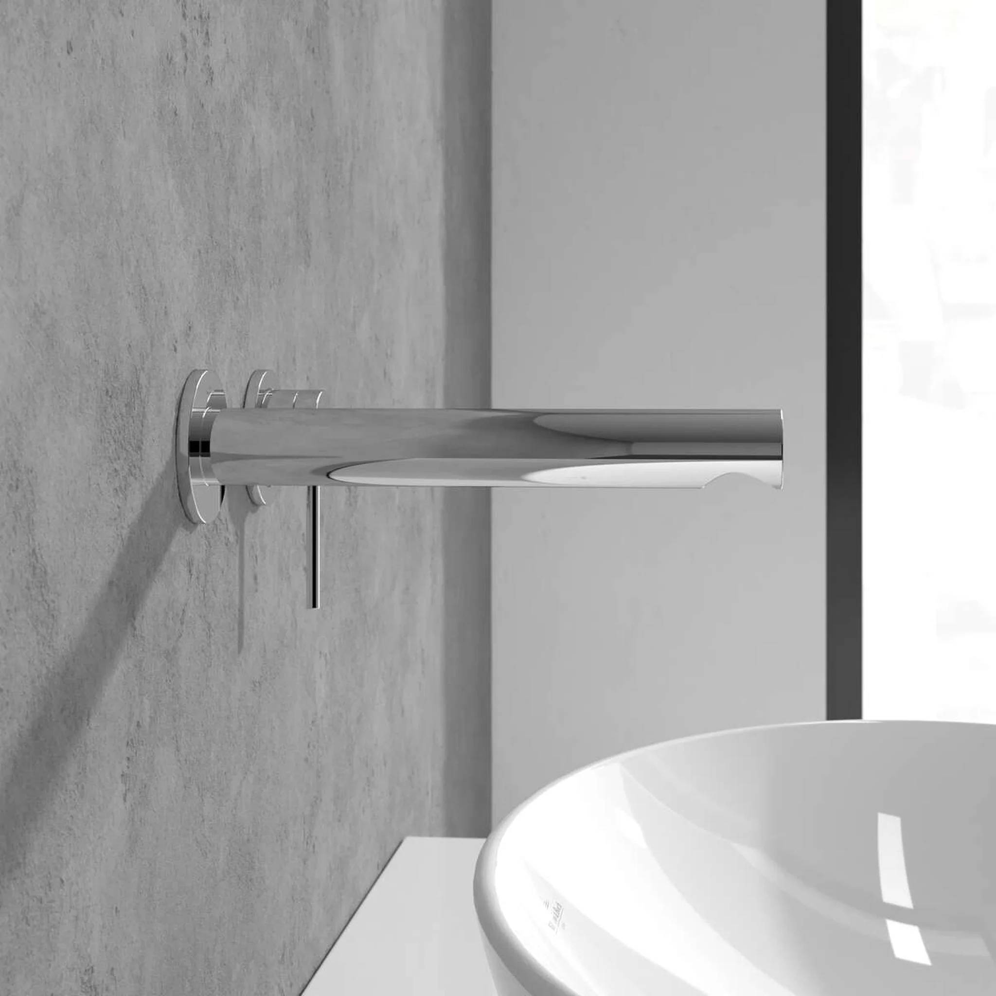 Moderner verchromter Wandwasserhahn über einem weißen Waschbecken an einer grauen Badezimmerwand.