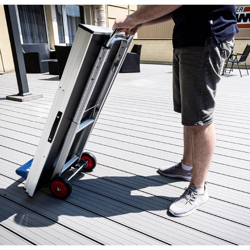Eine Person steht auf einem Deck und bedient einen Handwagen mit einer zusammenklappbaren Aluminiumrampe, höchstwahrscheinlich zur Bewegung großer Gegenstände.