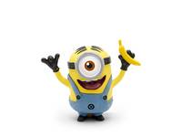 Ein lächelndes Minion-Spielzeug mit einem Auge, das einen blauen Overallanzug und schwarze Handschuhe trägt, hebt beide Arme und hält eine Banane.