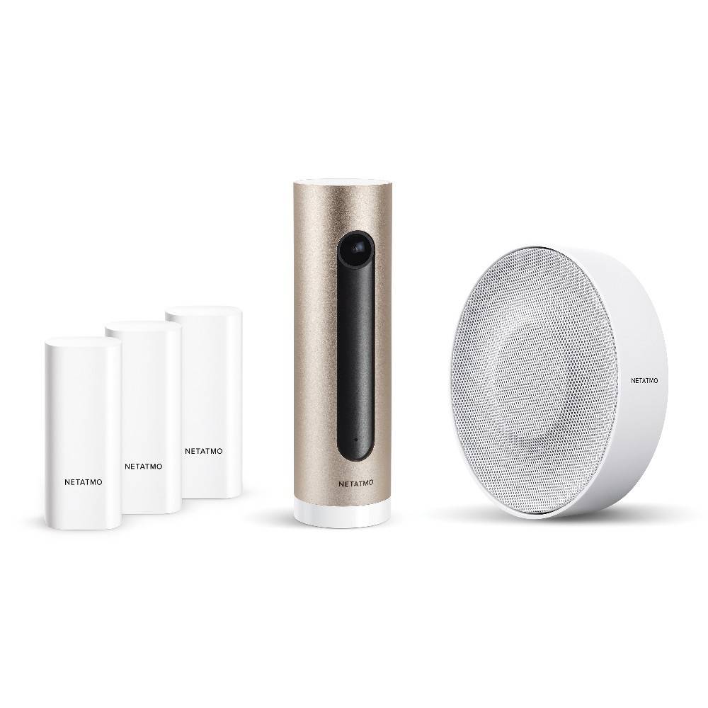 Ein intelligentes Heimsicherheitssystem-Set mit einer goldfarbenen Kamera, drei weißen Sensoren und einem runden weißen Lautsprecher, alle mit der Marke „Netatmo
