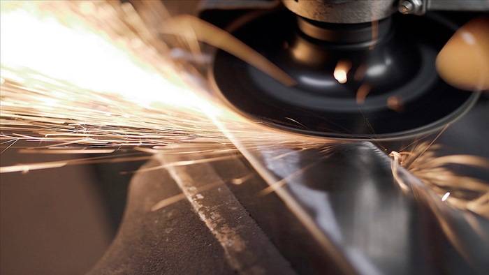 Eine Nahaufnahme einer Kreissäge, die gegen Metall schleift und helle Funken auswirft. Die Szene erfasst eine dynamische, industrielle Aktion im Gange.