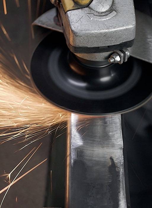 Ein Schleifrad sendet helle Funken aus, während es eine Metalloberfläche poliert und dadurch die schleifende Wirkung des Werkzeugs in einem industriellen Umfeld hervorhebt.