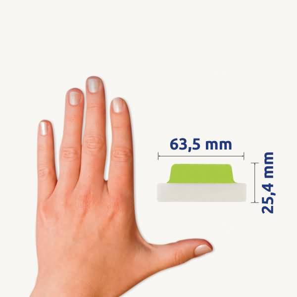 Hand neben einem kleinen knopfähnlichen Objekt mit beschrifteten Abmessungen von 63,5 mm Breite und 25,4 mm Höhe.