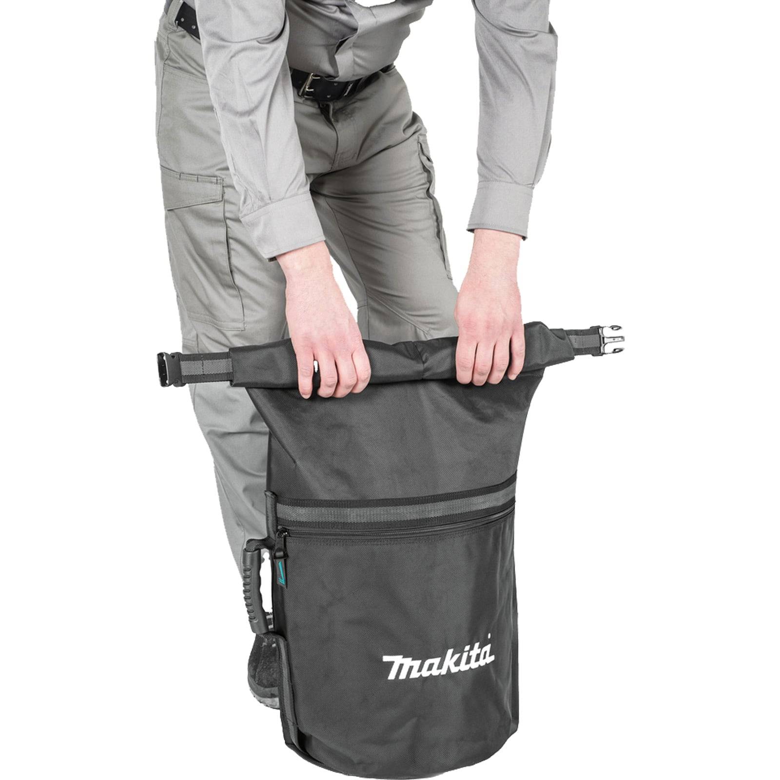 Eine Person in grauen Hosen und einem hellen Hemd hält einen schwarzen Makita-Staubsammelbeutel und bereitet sich darauf vor, ihn mit einer Klemmschnalle zu befestigen.