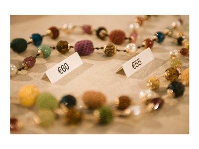 Farbenprächtige Perlenketten, die auf einem Tisch ausgelegt sind, mit Preisschildern, auf denen 