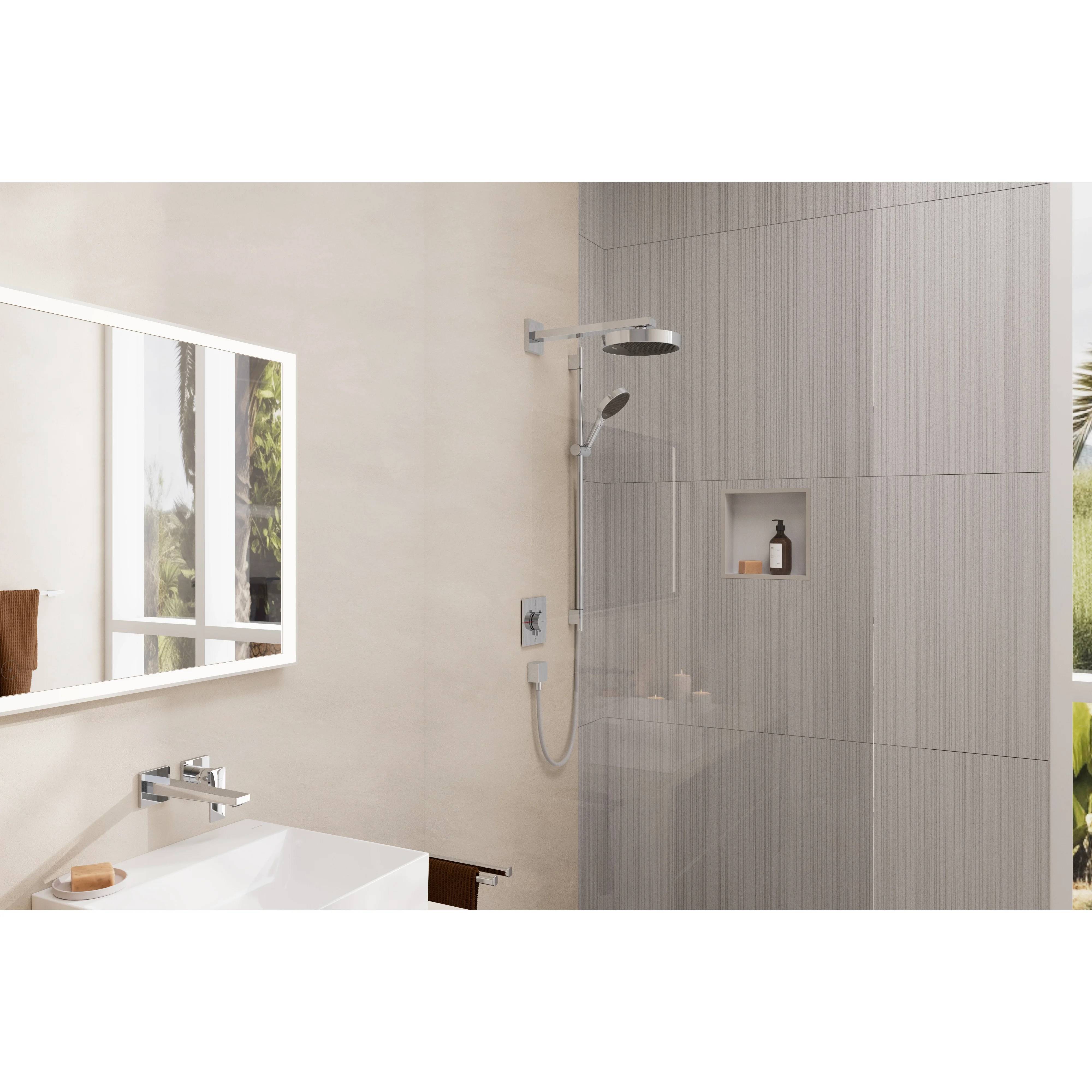 Modernes Badezimmer mit an der Wand montiertem Spiegel und Waschbecken, Duschbereich mit Glastrennung, Regendusche und eingelassener Ablage, die eine Flasche hält.