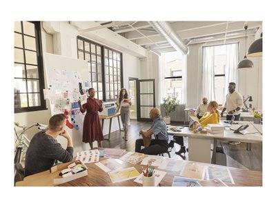 Eine Gruppe vielfältiger Fachleute arbeitet in einem hellen Büro zusammen. Eine Frau zeigt auf eine Präsentationstafel, während andere an einem Tisch diskutieren.