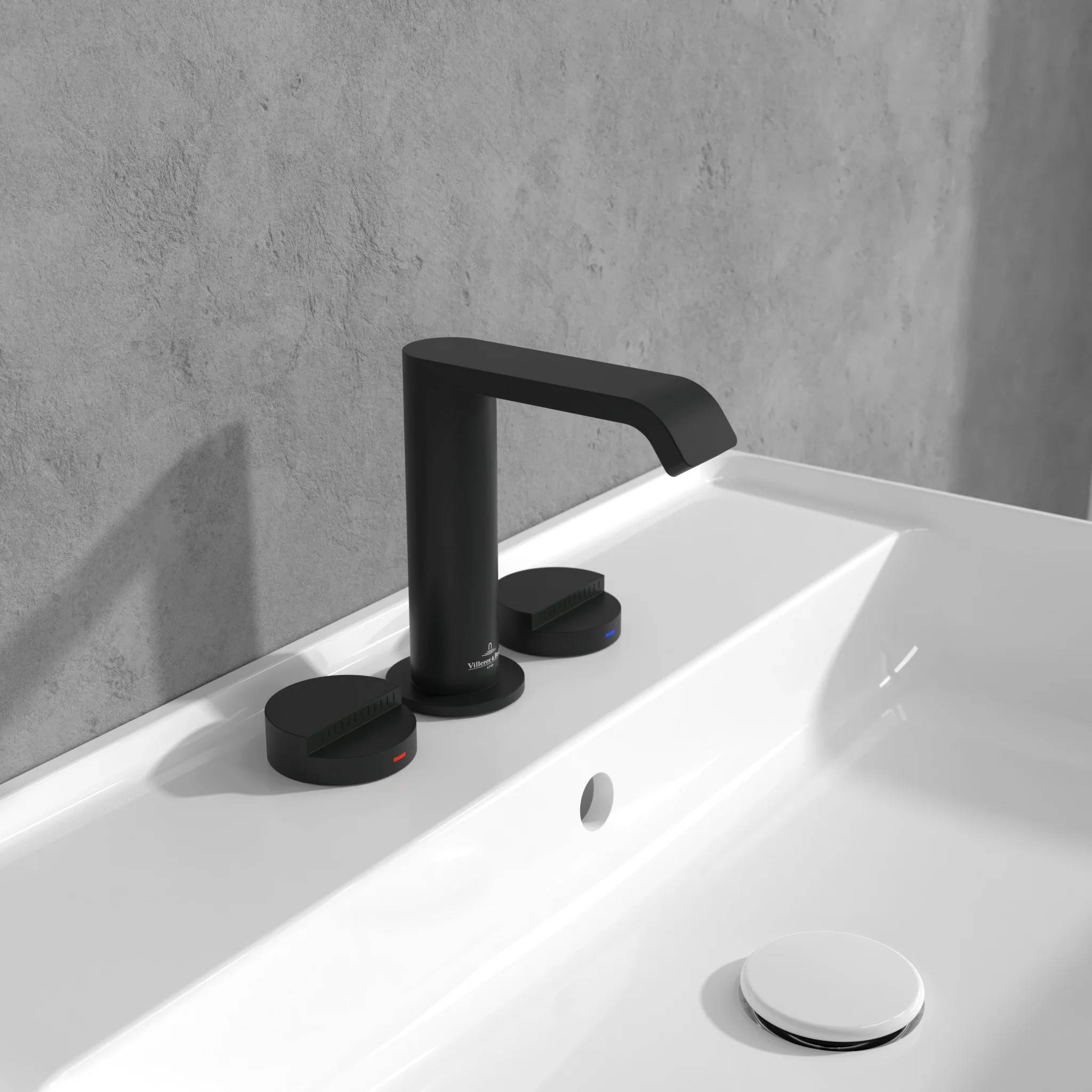 Schwarzer moderner Wasserhahn im Badezimmer auf einem weißen Waschbecken vor einer grauen Wand, mit zwei passenden Seitenbedienungen und einer runden Abdeckung des Abflusses.