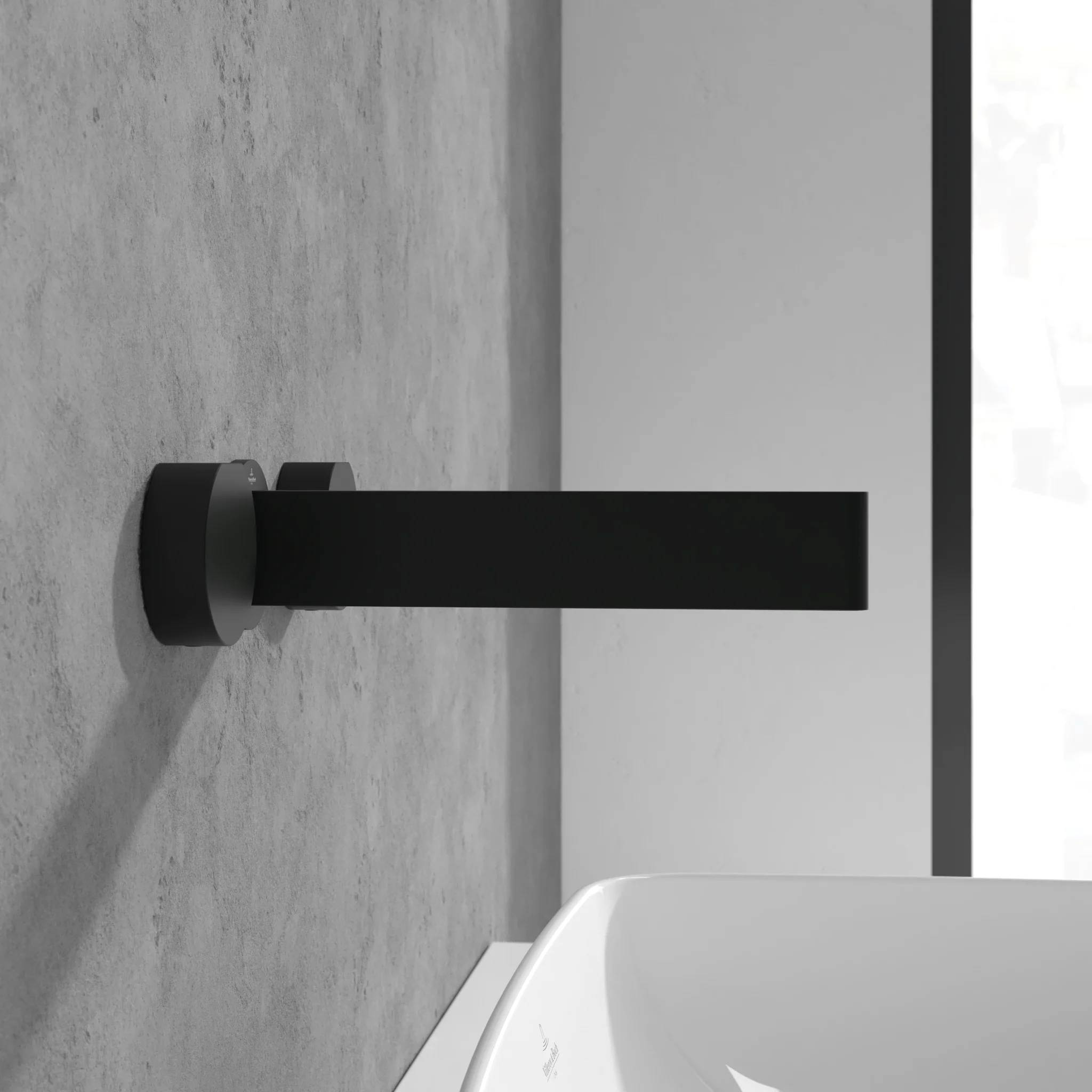 Modernes schwarzes, bodenmontiertes rechteckiges Pfosten oder Tischbein an einer Wand neben einem weißen, geschwungenen Waschbecken oder Armaturteil.
