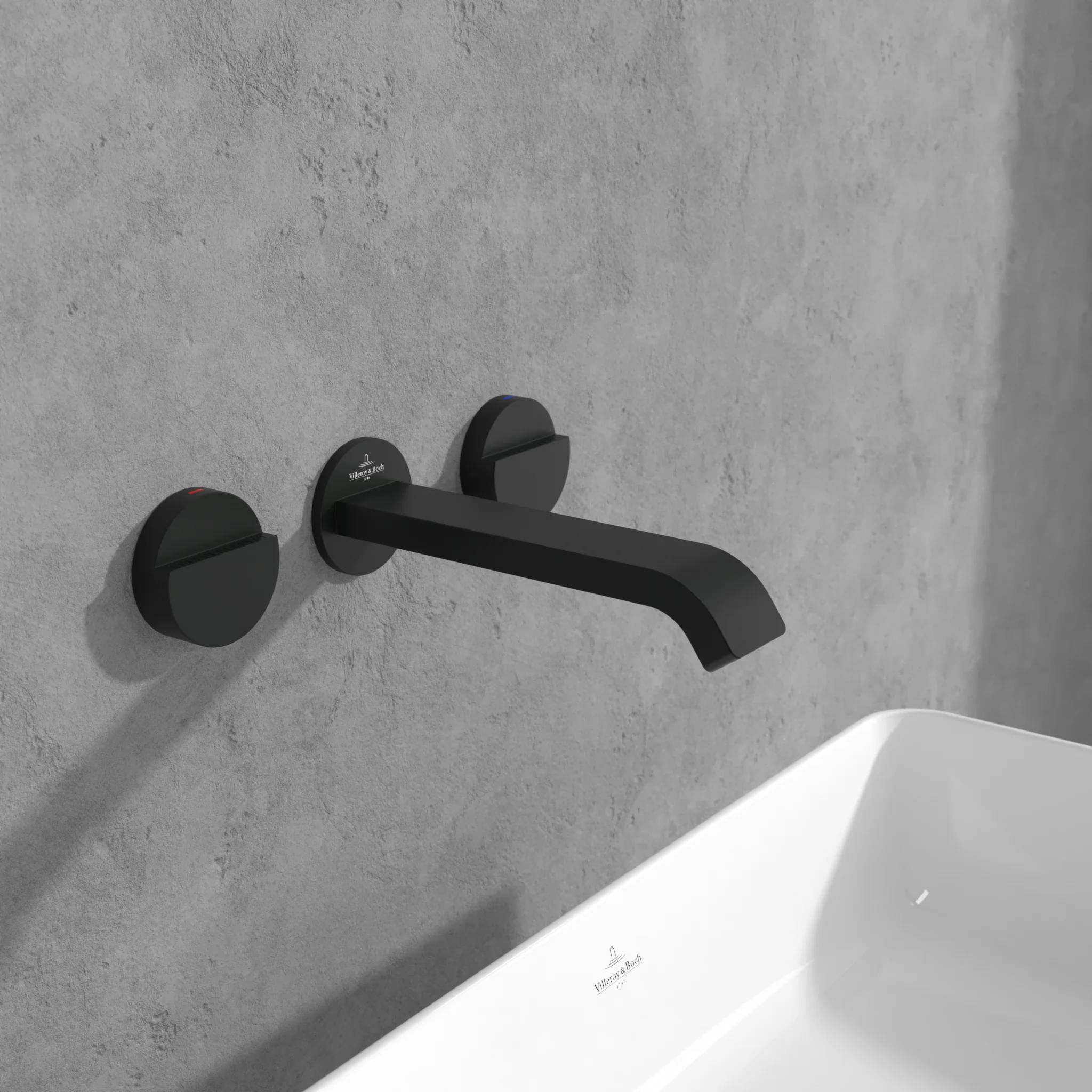 Minimalistischer schwarzer wandmontierter Badewannenhahn über einer weißen Wanne vor einer grauen Betonwand.