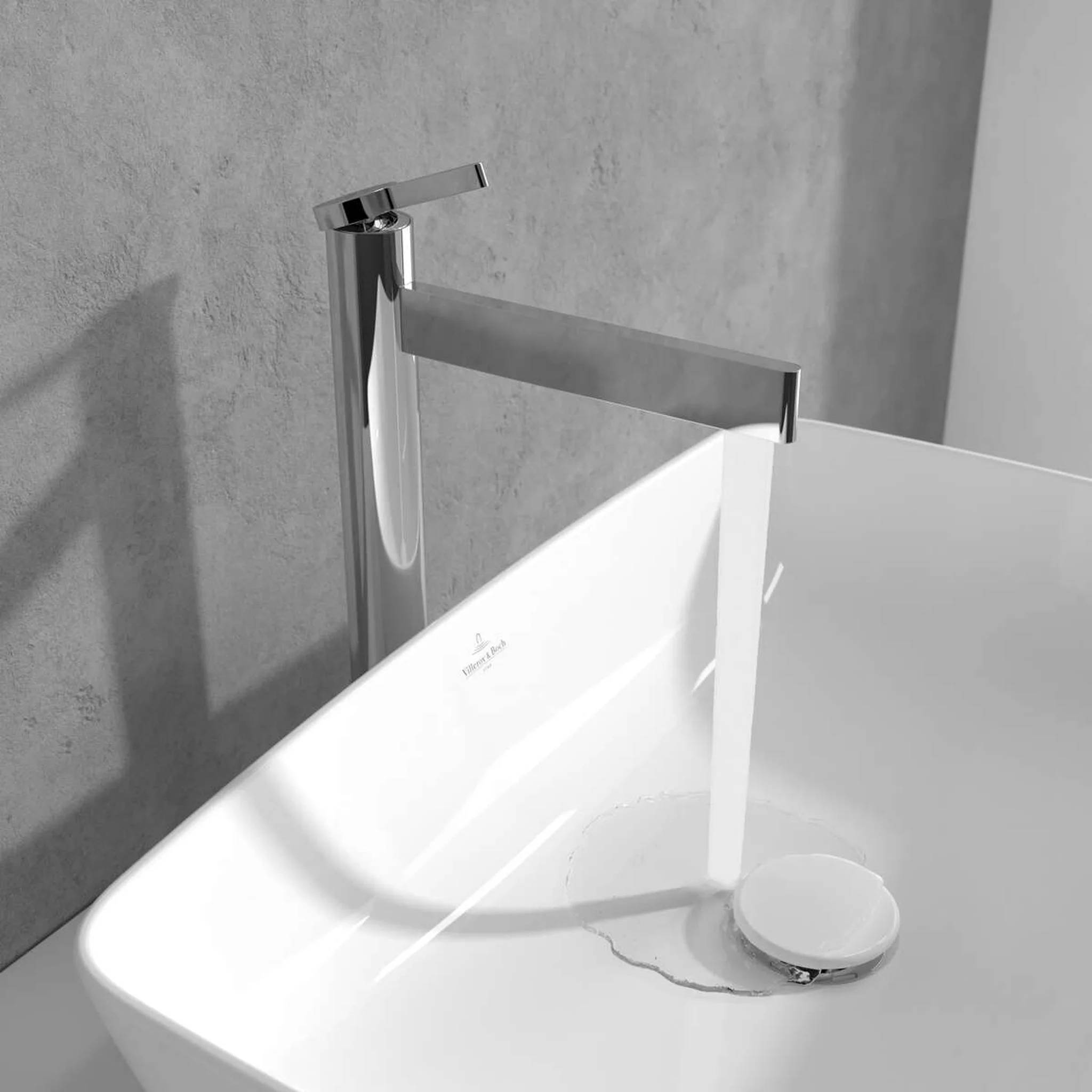 Moderne weiße Badewanne mit schlankem Chromwasserhahn und flacher Wasserfall-Auslaufstelle, die Wasser in die Wanne gießt
