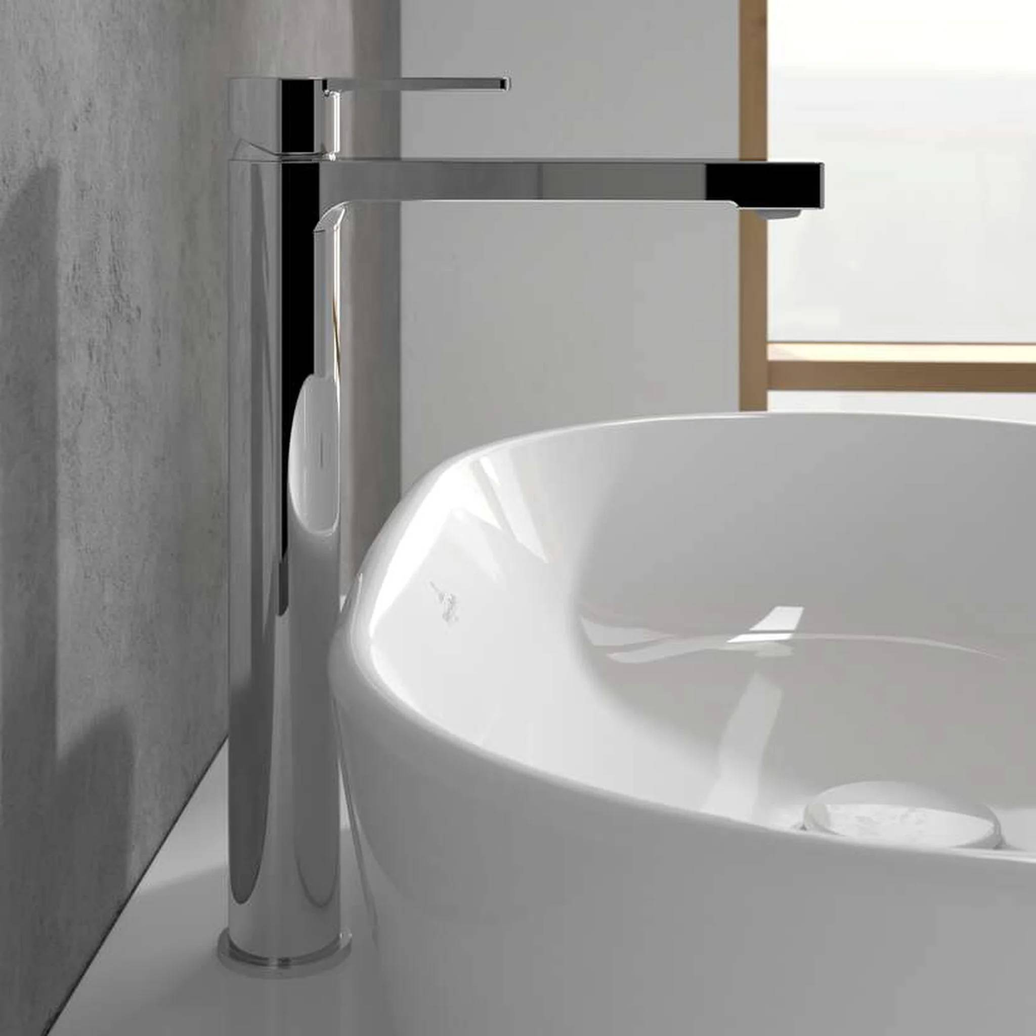 Moderner Chrom-Einhebelarmatur für das Badezimmer neben einem weißen Aufsatzwaschbecken vor einer grauen Wand und einem Fenster.
