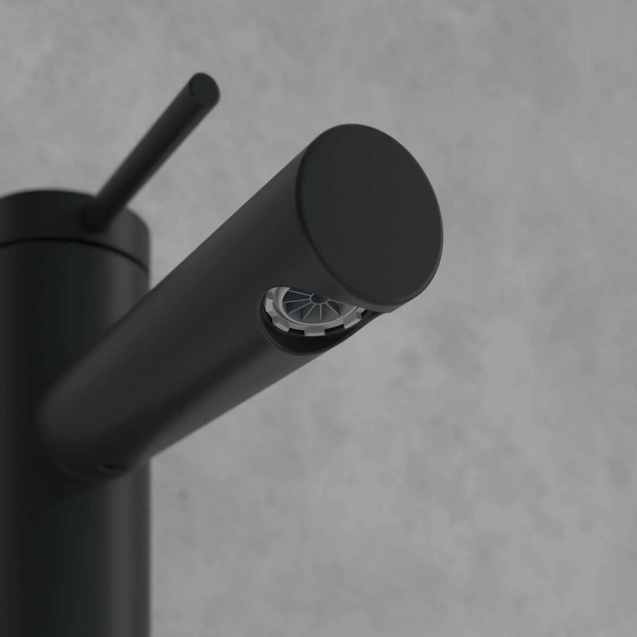 Nahaufnahme eines mattschwarz beschichteten Wasserhahnsauslaufs mit Luftsprudler vor einem einfachen grauen Hintergrund.