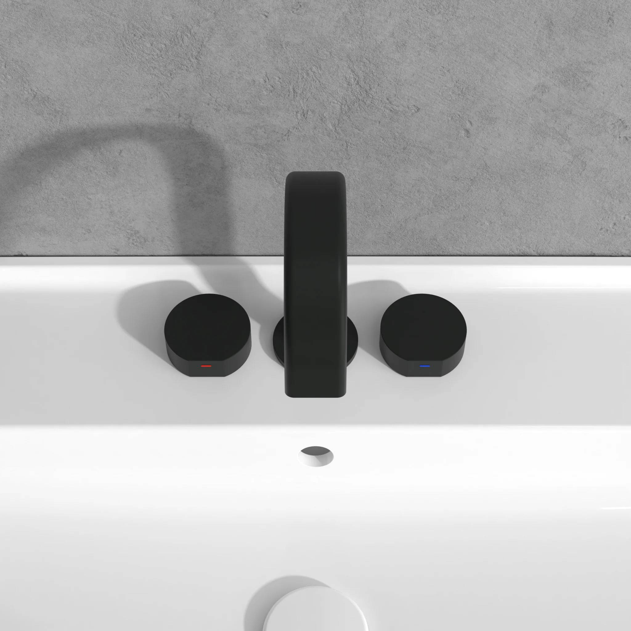 Modernes Badezimmerbecken mit schwarzem Wasserhahn und zwei runden Bedienelementen auf einem weißen Becken vor einer grauen Wand.