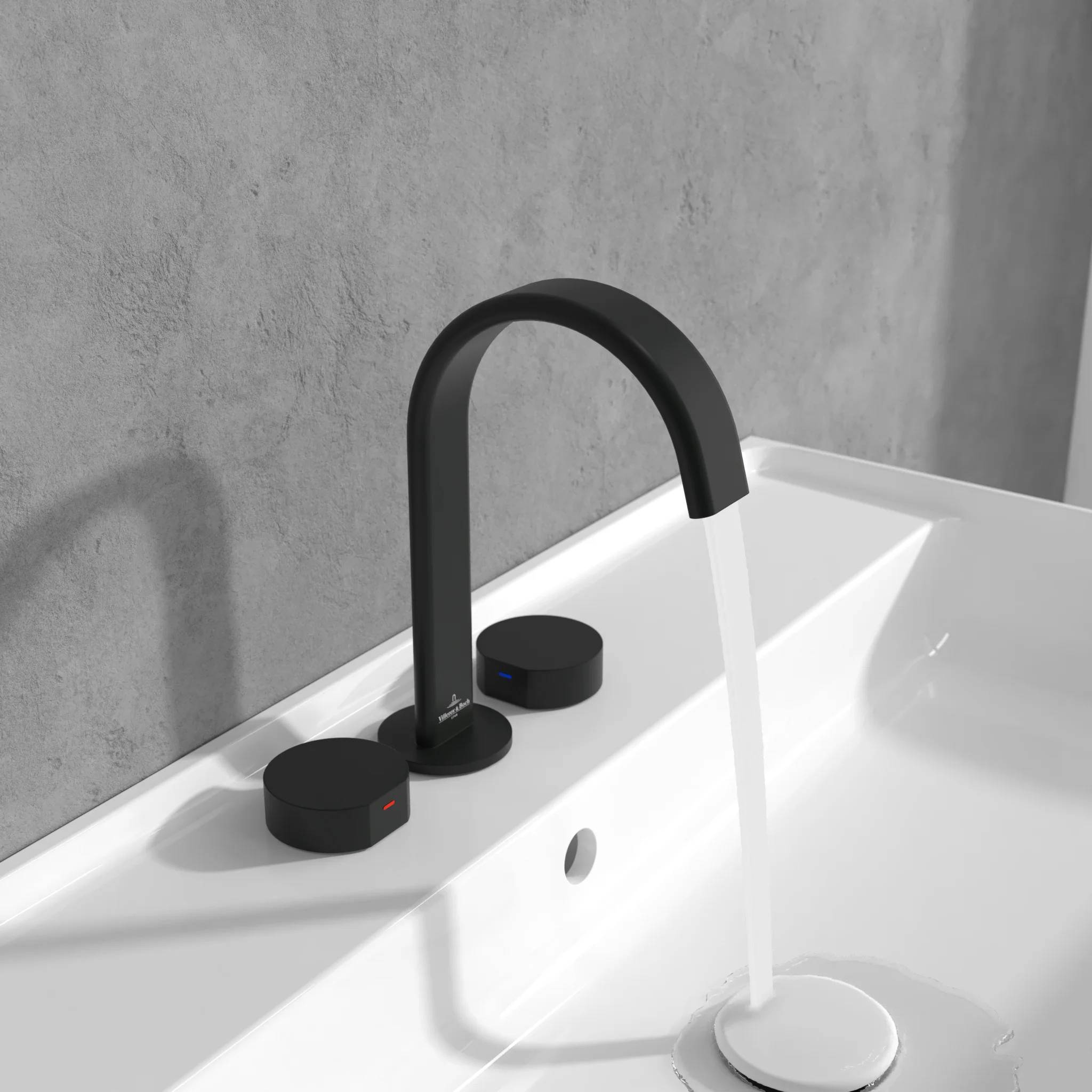 Moderner mattschwarzer Badezimmerhahn, der ein weißes Waschbecken mit Wasser füllt, mit zwei runden Bedienungsreglern auf der Arbeitsplatte.