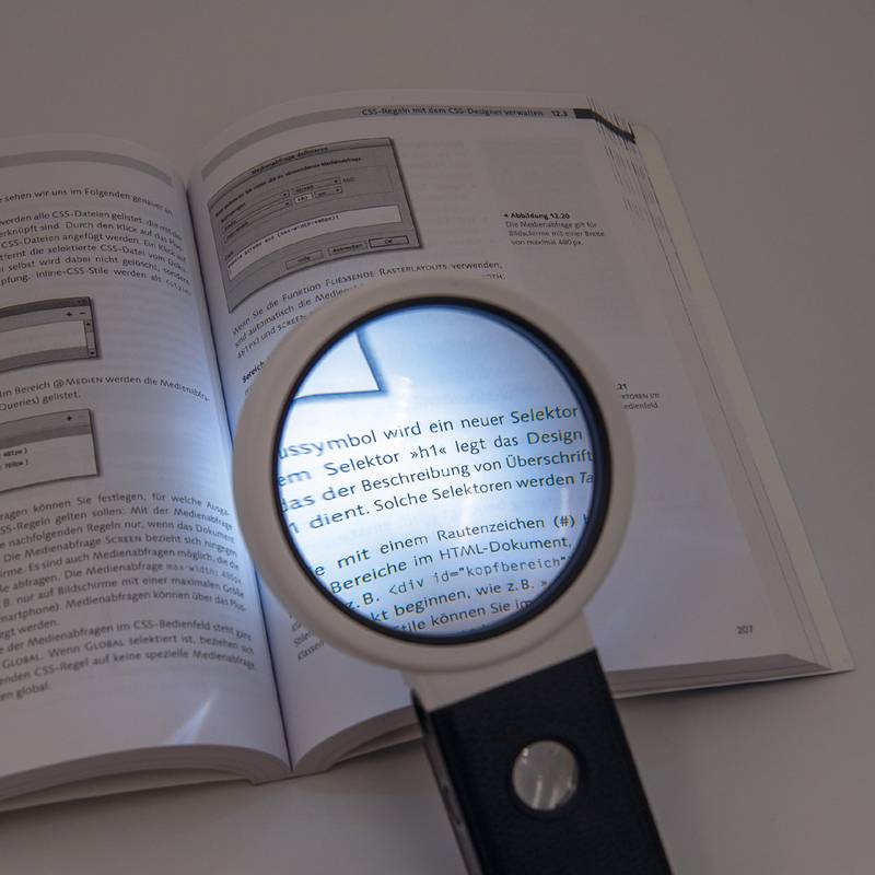 Lupe vergrößert deutschen Text in einem offenen Programmierbuch über CSS-Selektoren