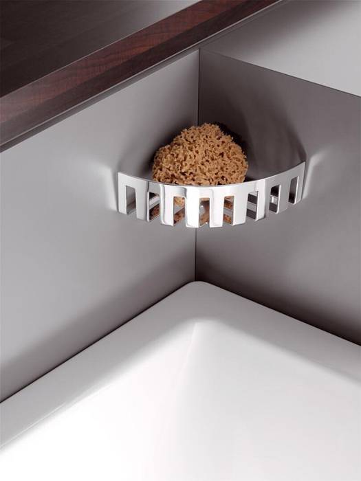 Ein natürlicher Schwamm wird in einem verchromten, wandmontierten Halter in der Ecke eines Badezimmers platziert, was modernes Design und Organisation unterstreicht.