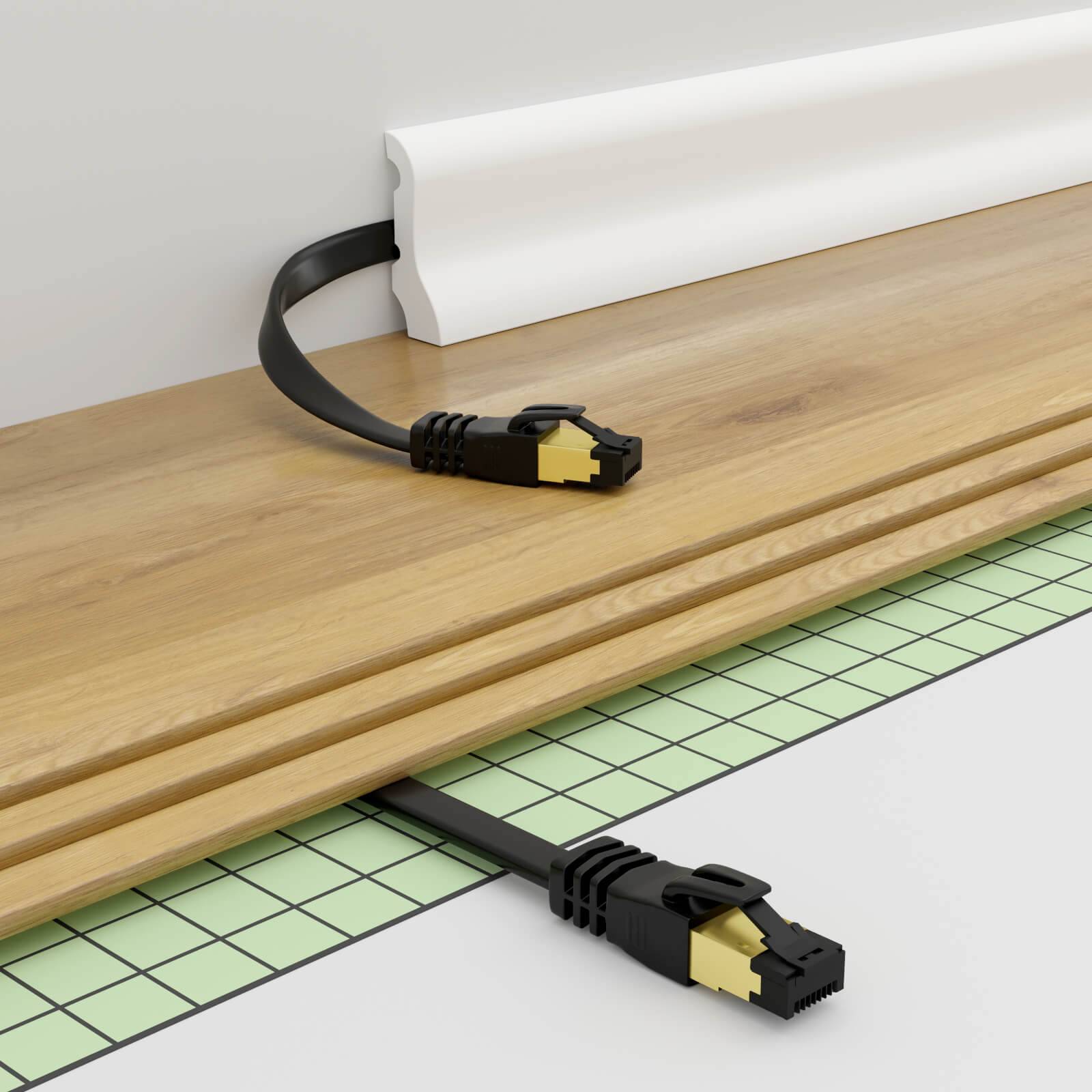 Netzwerkkabel, das durch eine Bodenspalte unter einem Holzbrett verläuft, mit sichtbaren RJ45-Steckern auf beiden Seiten.
