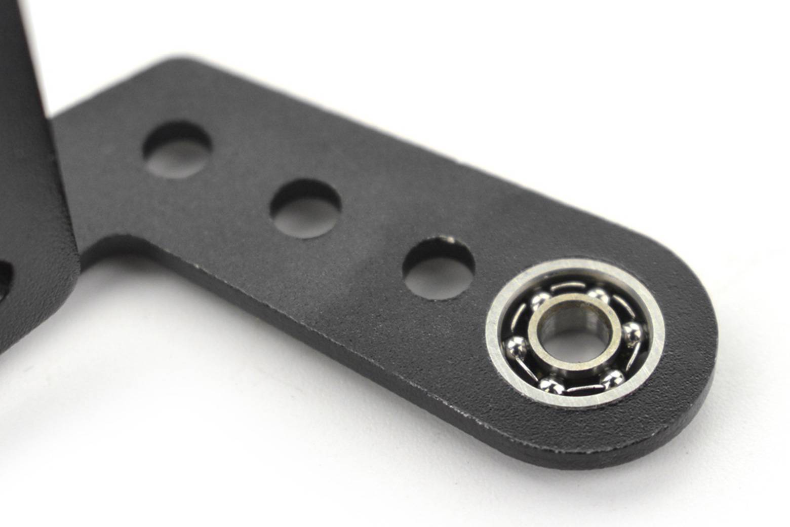 Eine Nahaufnahme einer schwarzen Metallklammer mit kreisförmigen Löchern und einem integrierten Kugellager an einem Ende, das in mechanischen Baugruppen verwendet wird.