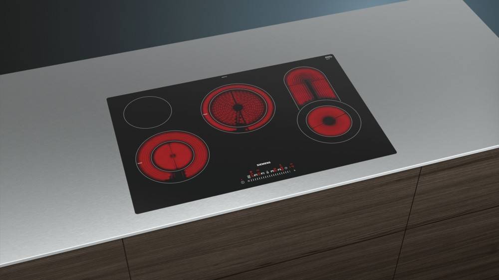 Eine elegante Induktionskochplatte mit rot glühenden Kochfeldern auf einer modernen Arbeitsplatte, die vier Heizzonen in verschiedenen Größen präsentiert.