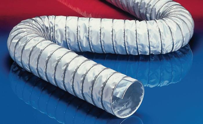 Metallische flexible Lüftungsschläuche, die auf einer rot-blauen Oberfläche aufgerollt sind.