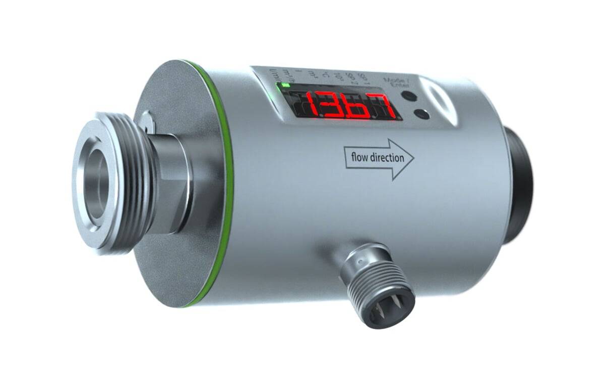 Ein metallischer Wasserdurchflusssensor mit digitaler Anzeige, die '1367' zeigt. Ein Pfeil gibt die Fließrichtung an. Zwei Anschlusspunkte sind sichtbar.