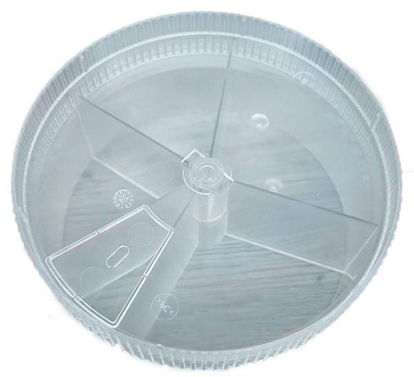 Ein klarer, runder Plastikdeckel mit einer dreieckigen Einbuchtung und zwei kleinen Kreisen, offensichtlich für einen Transportbehälter konzipiert.