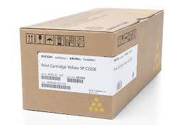 Ein beschrifteter Karton mit einer gelben Druckerpatrone, Modell SP C220E, mit Versandetiketten und sichtbaren Handhabungssymbolen.