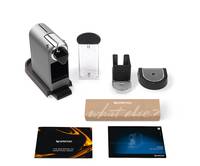 Verschiedene Nespresso-Kaffeemaschinen-Teile und Zubehör, darunter ein Kapselhalter, Kapseln und original verpacktes Zubehör auf weißem Hintergrund.