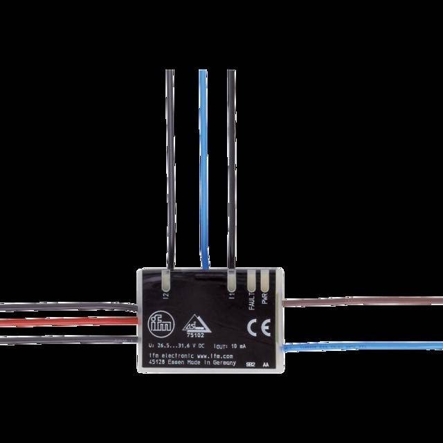 Eine schwarze elektronische Komponente mit vier herausragenden Drähten, beschriftet mit 'Ue 26.5...31.6 VDC' und 'ifm electronic gmbh', was auf ein technisches Gerät hinweist.