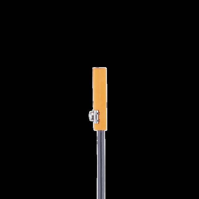 Eine einzelne hohe Straßenlaterne mit einem orangefarbenen rechteckigen Leuchtengehäuse, das an einem grauen Mast befestigt ist, vor einem einfarbigen schwarzen Hintergrund.