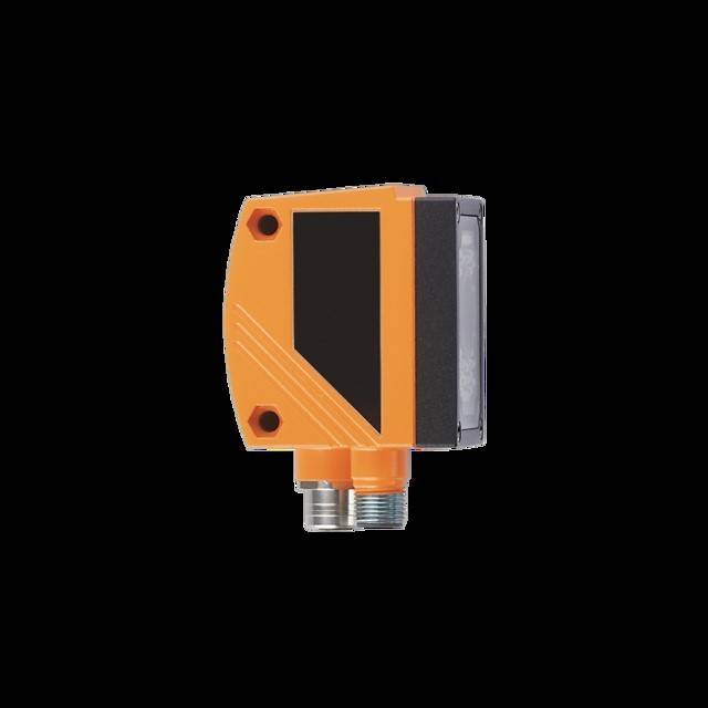 Ein orangefarbener industrieller Sensor mit einer schwarzen Vorderseite und zwei Metall-Anschlussports am unteren Ende, vor einem schwarzen Hintergrund.