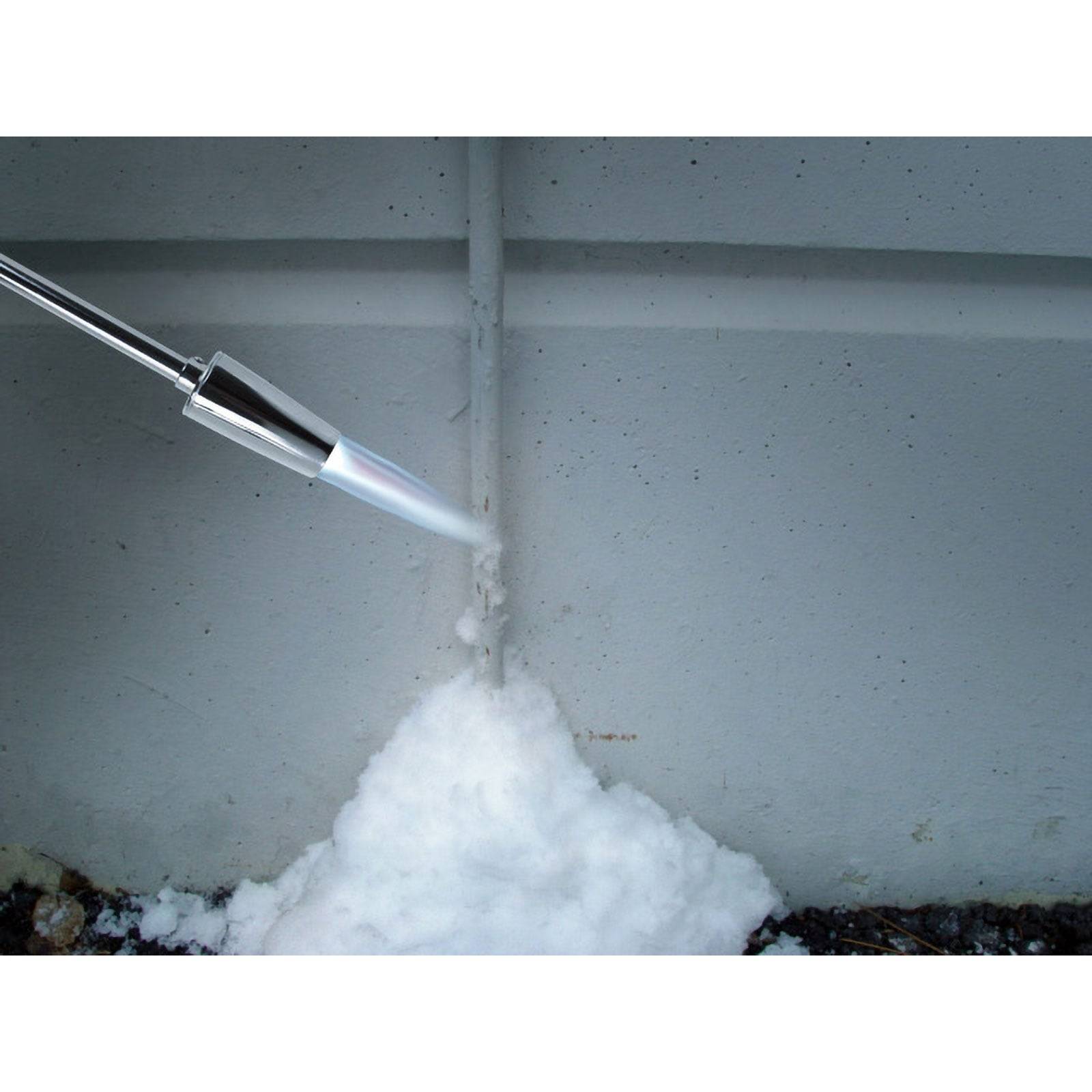 Schneefräse mit einer Düse, die Schnee gegen eine Wand sprüht und einen Schneehaufen bildet.