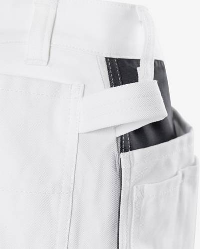 „Nahaufnahme eines weißen Kleidungsstücks mit einer Tasche und schwarzer Einfassung, die Stickerei und Gewebestruktur im Detail zeigt.