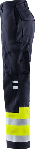 Detailaufnahme eines dunkel gefärbten Kleidungsstücks mit metallischen Akzenten, möglicherweise Teil einer Uniform oder Arbeitskleidung, mit Fokus auf Taschen und Nähte.