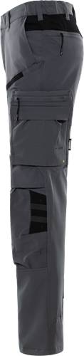 Eine Nahaufnahme eines schwarzen Nylon-Rucksacks mit mehreren Fächern und sichtbaren Nahtdetails vor einem dunklen Hintergrund.
