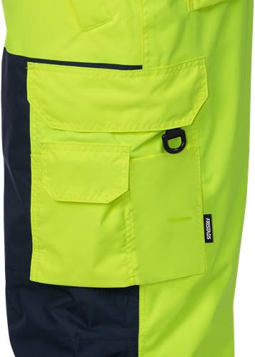 Nahaufnahme eines neongelben und schwarzen Kleidungsstücks mit einer Tasche und einer Schlaufenbefestigung. Das Markenetikett 