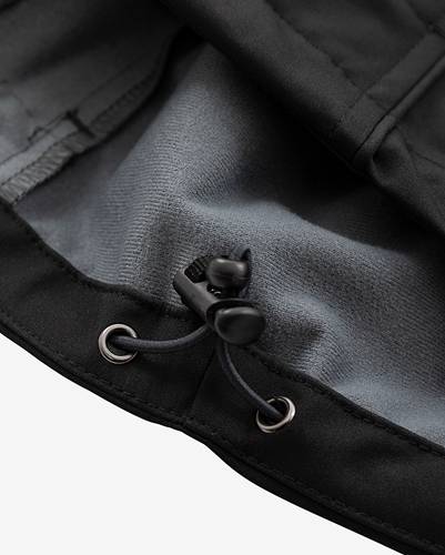 Nahaufnahme der Kordelzugschnur und des Toggleverschlusses einer schwarzen Jacke, die Webestruktur des Stoffs und Nahtdetails hervorhebt.