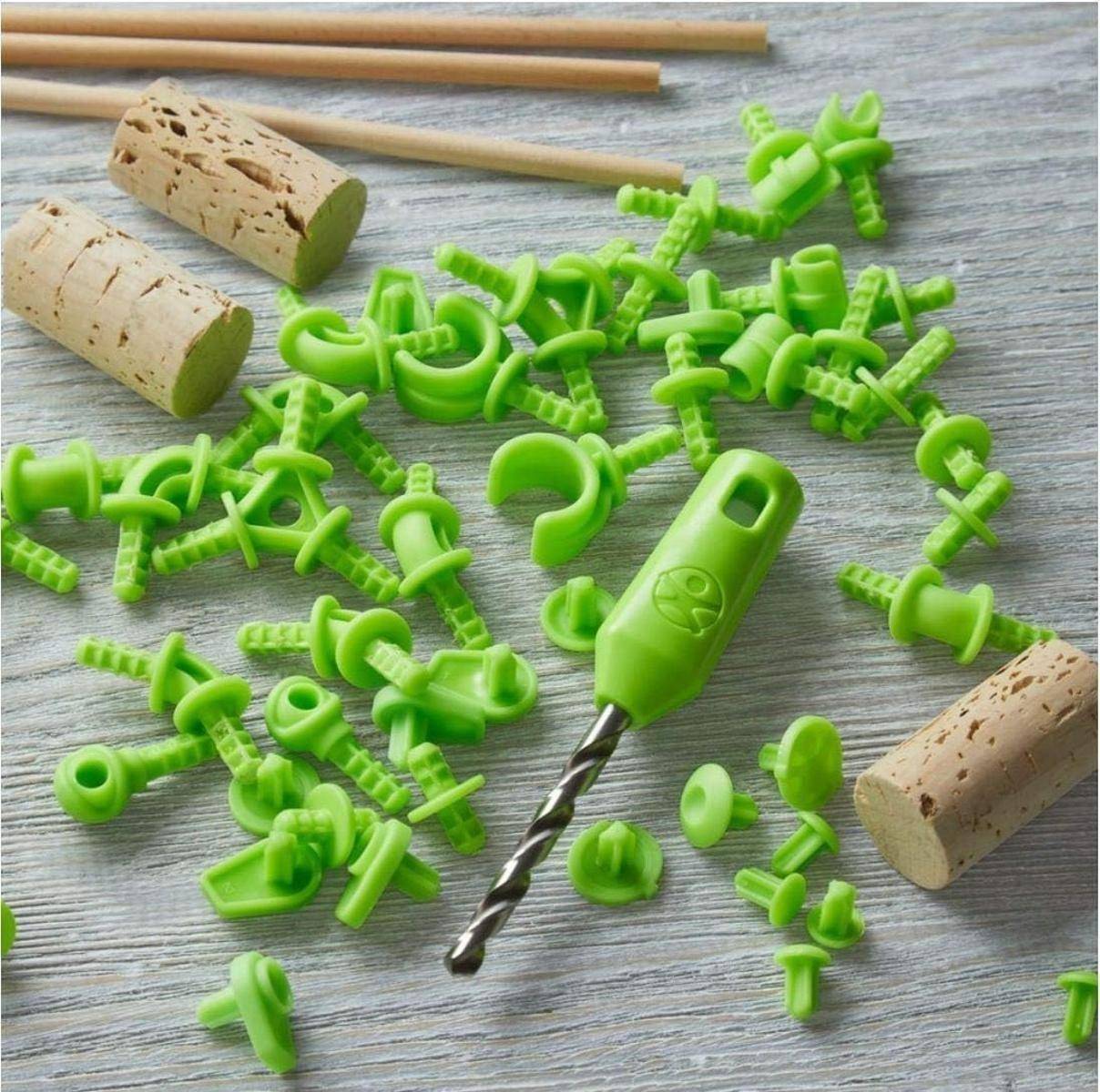 Grüne Kunststoffbohrer-Verbindungsstücke und Weinkorken auf einer grauen Holzoberfläche angeordnet, mit einem kleinen Bohrer, der an einem Verbindungsstück befestigt ist.