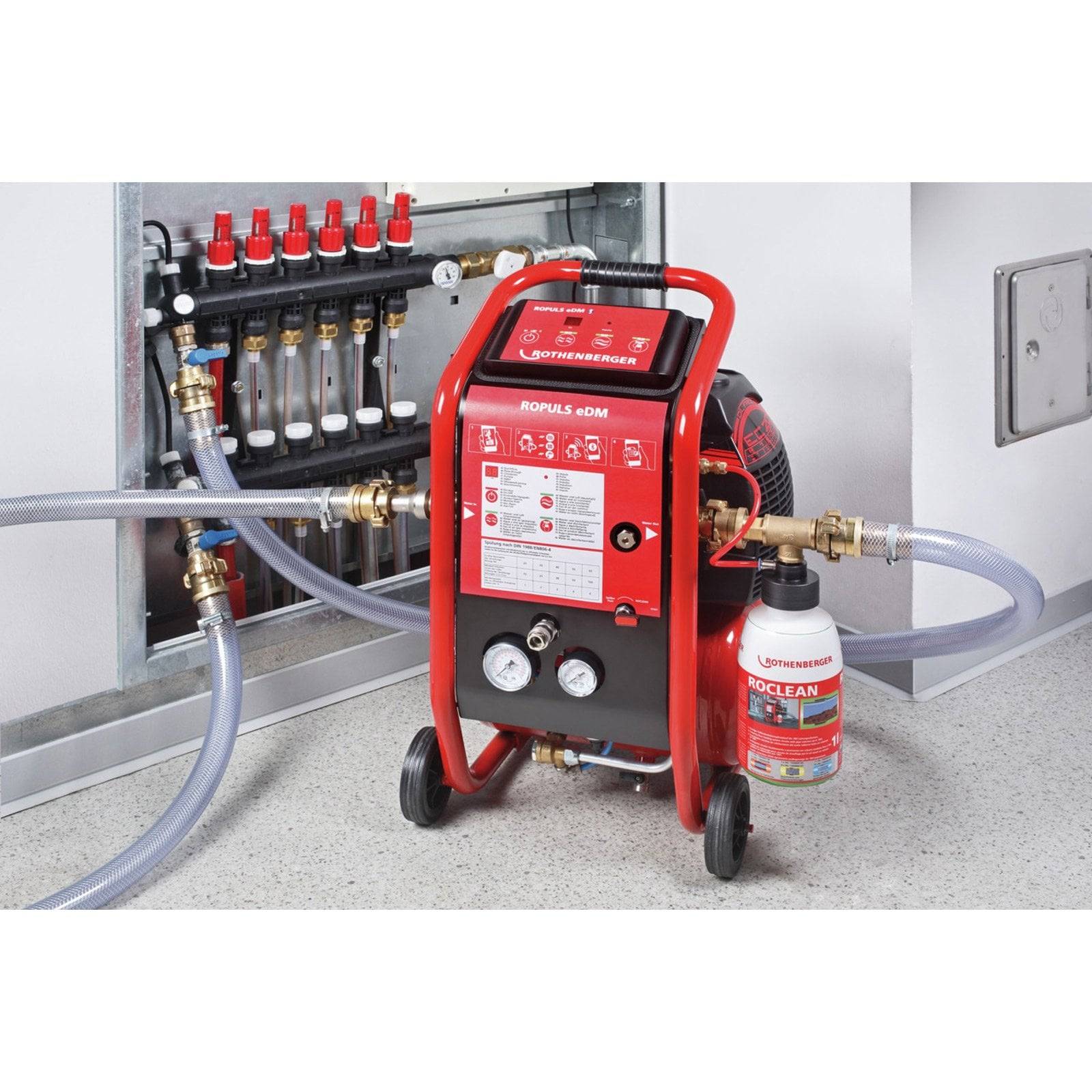 Eine rote Spülmaschine, die mit einem Heizungssystem verbunden ist, mit beschrifteten Rohranschlüssen und einem ProClean Flüssigkeitsbehälter zur Systemreinigung.