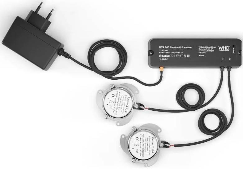 Bluetooth-Empfänger, der mit einem Stromadapter verbunden ist, und zwei kabelgebundene runde Lautsprecher auf weißem Hintergrund.