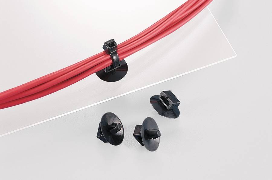 Rote Kabel sind mit einer schwarzen Klemme befestigt. Drei schwarze Kabelbefestigungen sind in der Nähe auf einer weißen Oberfläche platziert.