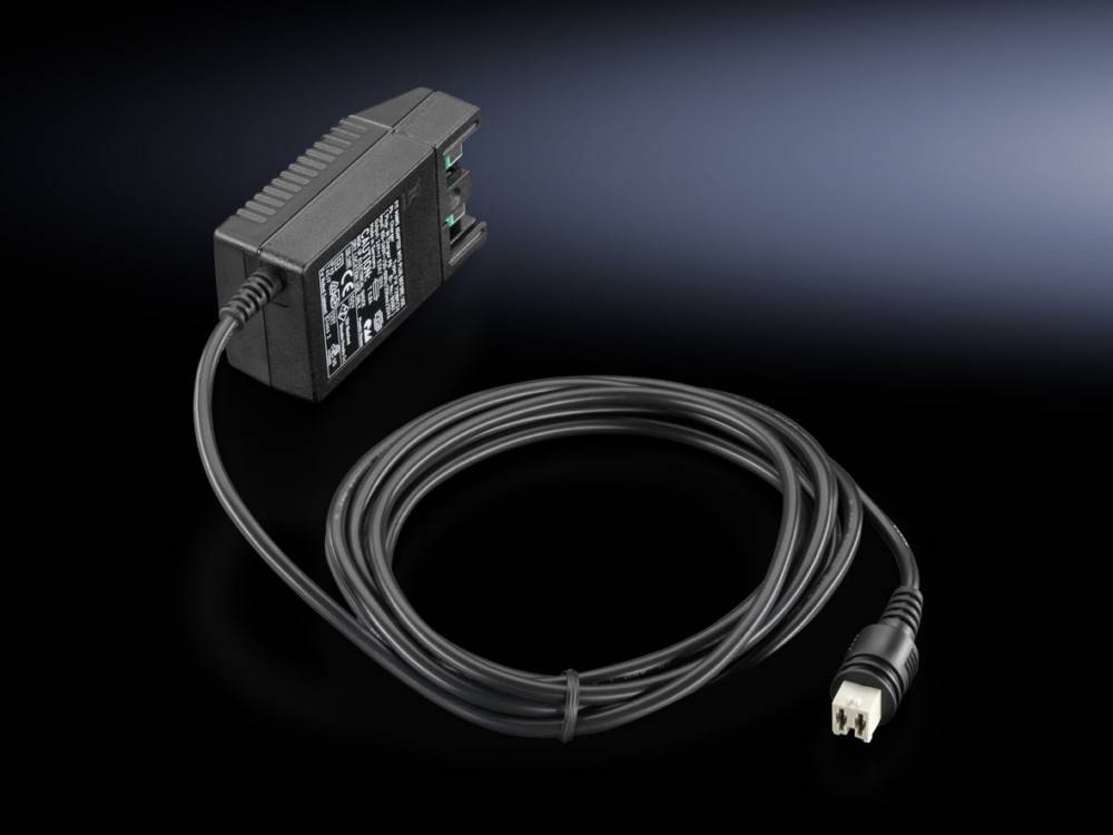 Ein schwarzes Netzteil mit Kabel, versehen mit zwei grünen Anschlussklemmen an einer Seite. Das Netzteil liegt auf einer dunklen Oberfläche.