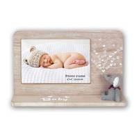 Ein Babyfoto, das in einem Holz-Tischrahmen mit dekorativen Elefanten- und Herz-Akzenten angezeigt wird.