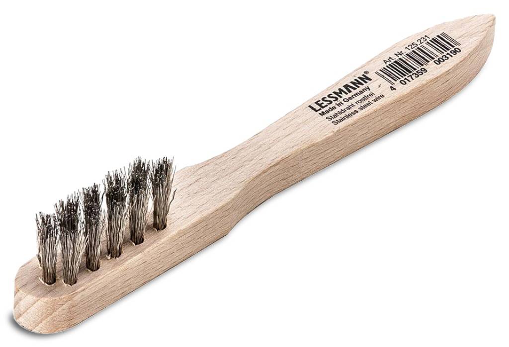 Eine Holzhandbürste mit abgenutzten Metallborsten und einem flachen Griff mit der Aufschrift „LESSMANN