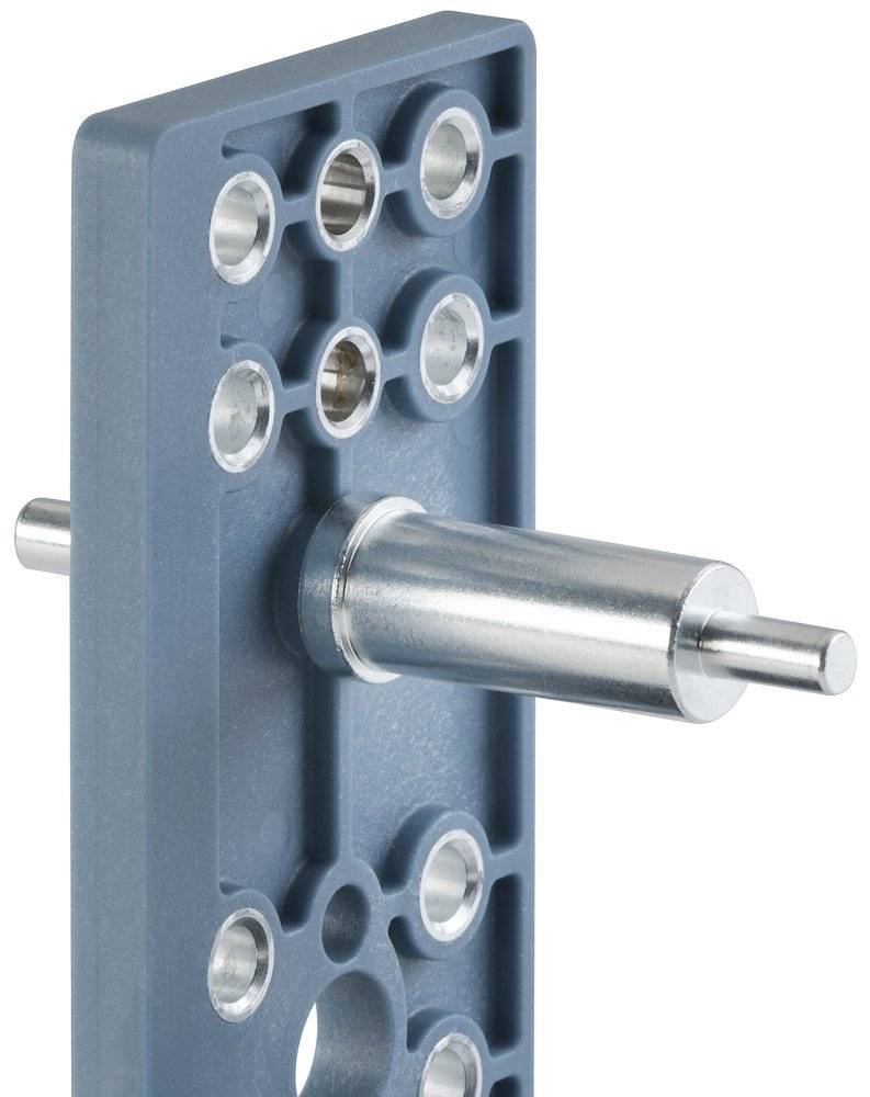 Ein Metallstab erstreckt sich horizontal von einer rechteckigen grauen Platte mit mehreren kreisförmigen Löchern.