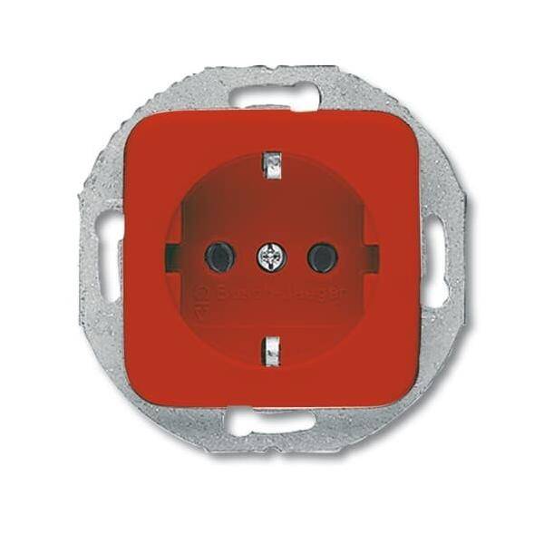 Eine rote elektrische Wandsteckdose mit einem metallfarbenen Rahmen ist zu sehen. Die Steckdose verfügt über zwei runde Löcher und eine zentrale Schraube.