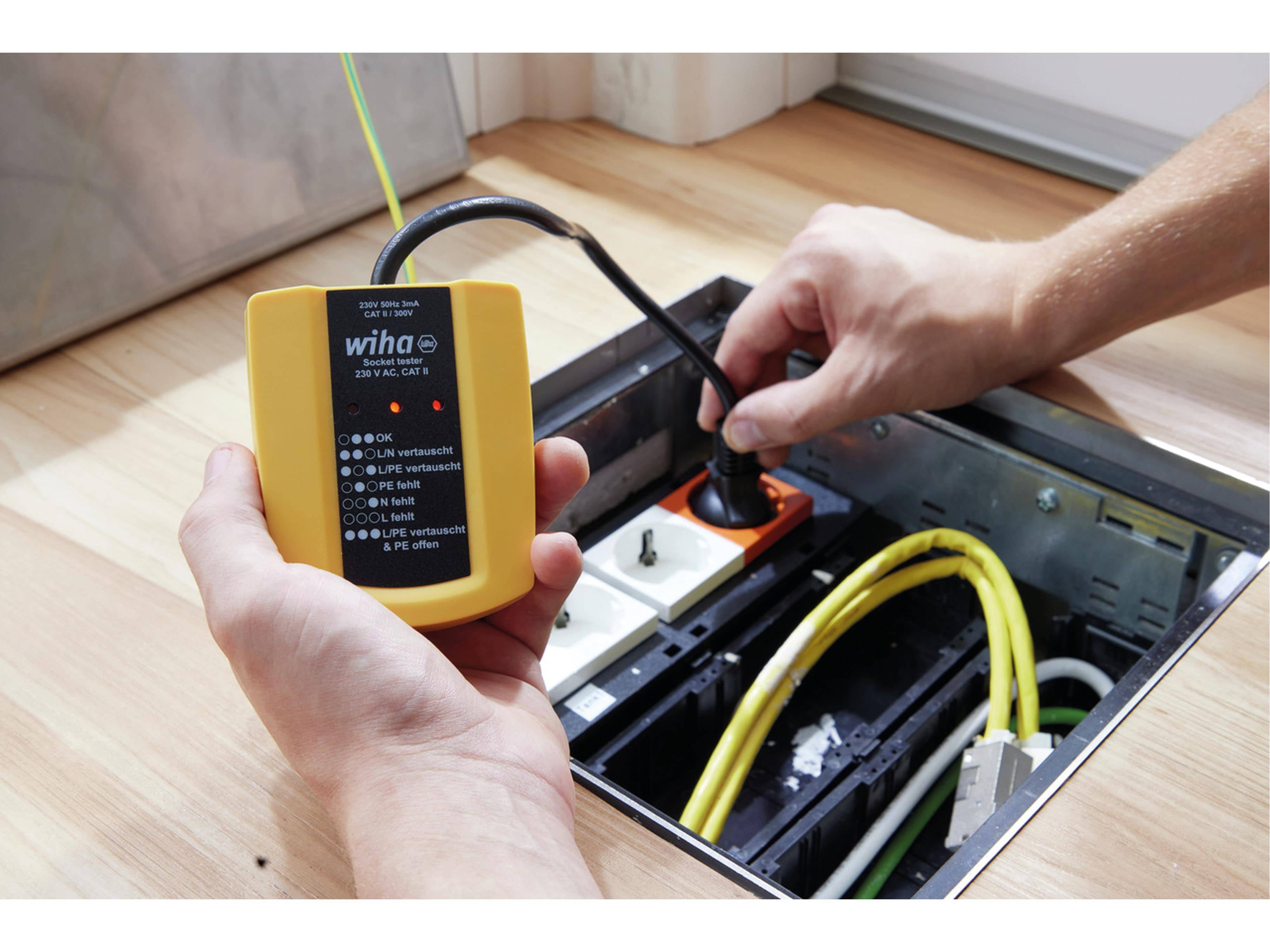 Eine Person nutzt ein tragbares Elektrotestgerät, um Verbindungen in einer Bodensteckdosenleiste zu überprüfen und dabei ordnungsgemäße Spannung und Verdrahtung sicherzustellen.