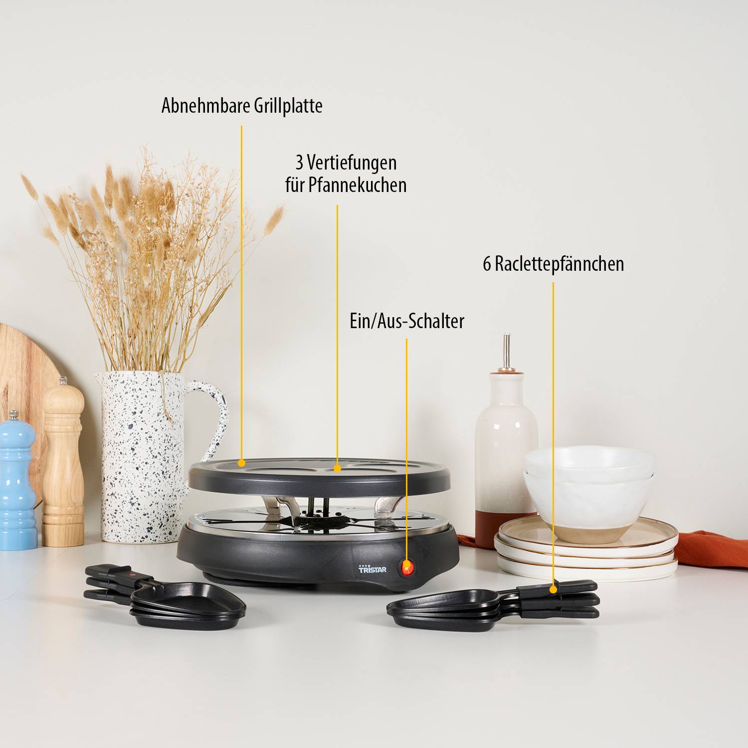 Beschriftete Küchentheke-Grill mit Bezeichnungen, die abnehmbare Grillplatte, 3 Pfannkuchen-Mulden, Ein-/Ausschalter und 6 Raclette-Pfannen zeigen.
